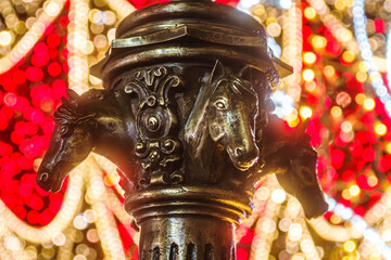 Zabytkowe poidło końskie na rynku w Opolu w świątecznej oprawie. Detal rzeźbiarski z głowami koni na tle kolorowych iluminacji bożonarodzeniowych. Nastrojowe ujęcie z efektownym bokeh. © Henryk Niestrój