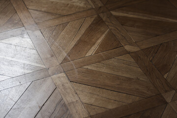 Obraz premium A warm wooden parquet floor featuring a geometric pattern of triangles and planks