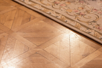 A close view of a polished parquet floor transitioning to a decorative floral rug