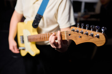 Fototapeta premium Closeup of artist showcasing focused guitar playing energy. Ambitious musician delivers heartfelt performance with yellow electric instrument in cozy rehearsal environment