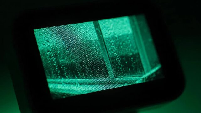 Rain drops on window viewed through a green screen monitor, showing the window and rain.