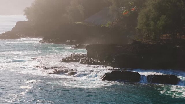 Waves crashing on rocky coast sunny day drone video Hawaii Kauai 4K