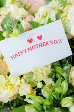 beautiful floral bouquet with a happy mother's day card , featuring pastel roses, lisianthus, and greenery.pale pink roses.pink blossom flower bouquet