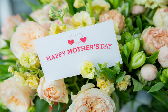 beautiful floral bouquet with a happy mother's day card , featuring pastel roses, lisianthus, and greenery.pale pink roses.pink blossom flower bouquet