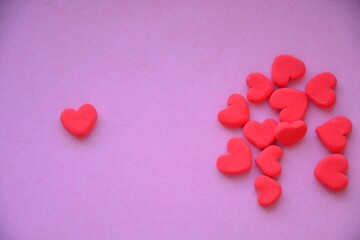 Obraz premium Small red hearts on a pink background with copy space. One heart is separated from the group, symbolizing choice or uniqueness.