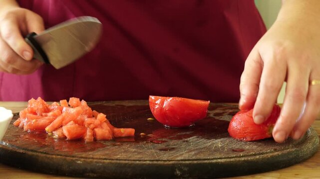 Woman cooking sauce with fresh tomato at the kitchen