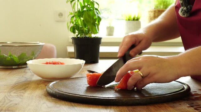 Woman cooking sauce with fresh tomato at the kitchen