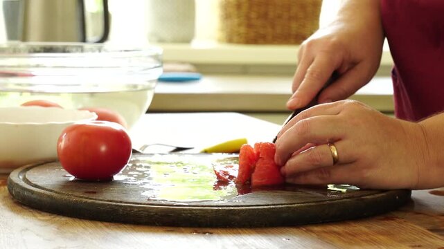 Woman cooking sauce with fresh tomato at the kitchen