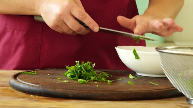 Woman cooks and using fresh basil leaves from bush