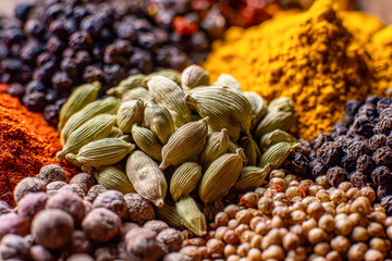 Obraz premium Assorted aromatic spices including cardamom pods, turmeric, peppercorns, and coriander seeds arranged vibrantly to showcase vibrant color and texture variety