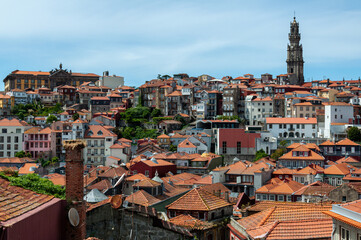 Fototapeta premium Looking across the rooftops of the colourful city of Porto under cloudy skies, with the famous landmark, the Torre dos Clerigos, in the background 