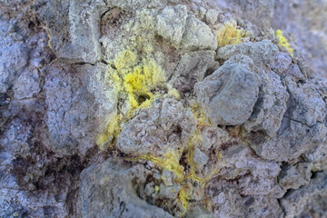 Bright yellow mineral deposits contrast sharply with rough grey rock in a remote area of Russia, highlighting the beauty of its natural geological formations.
