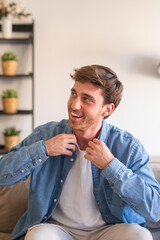 Fototapeta premium Portrait of young caucasian man indoor sitting on couch relaxing, smiling and laughing with confidence, enjoying the moment. Cheerful guy at home having fun.