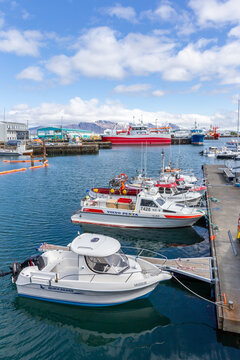 Motorboats and fishing vessels docked in Reykjavik harbor with Mount Esja
