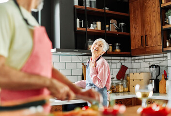 Fototapeta premium Portrait of happy senior mid aged mature couple prepering meal with fresh vegatebles in kitchen at hpme