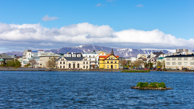 Reykjavik skyline with colorful buildings by Tjornin lake and Mount Esjan, Iceland.