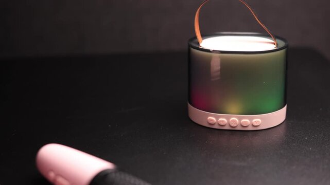 Portable karaoke microphones and colorful LED speaker on a dark surface