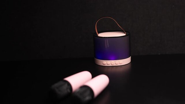 Portable Bluetooth speaker with ambient lighting and a leather handle on a dark background