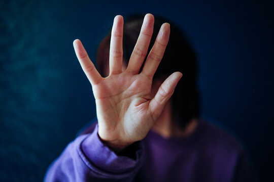 Womans hand blocking face, showing refusal gesture. Concept of domestic abuse, violence, harassment, privacy protection, and rejection.