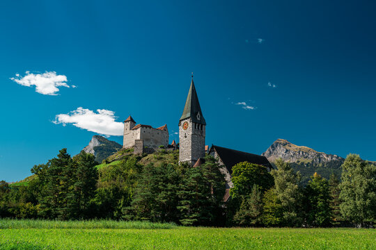 Medieval Gutenberg Castle and St Nicholas Church in Balzers Liechtenstein, historic alpine landmark under blue sky, ideal for European travel guides.