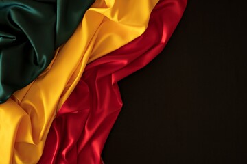 Fototapeta premium Black History Month background. Red, yellow, green colors drapery, silk flag on black background. Top view