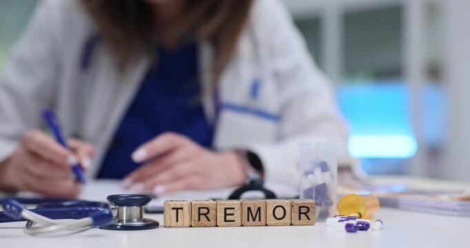 Word Tremor on wooden blocks with stethoscope and pills on desk. Doctor diagnoses involuntary rhythmic muscle contraction and relaxation in hospital