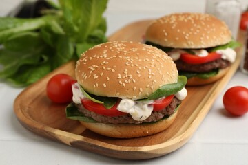 Delicious burgers with meat patties on white table, closeup