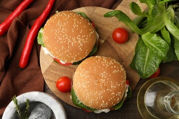 Naklejka premium Delicious burgers with meat patties on wooden table, flat lay