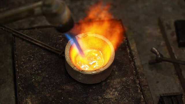 Manual gold melting using a torch before casting jewelry 4k video. Gold being melted by torch during jewelry production.
