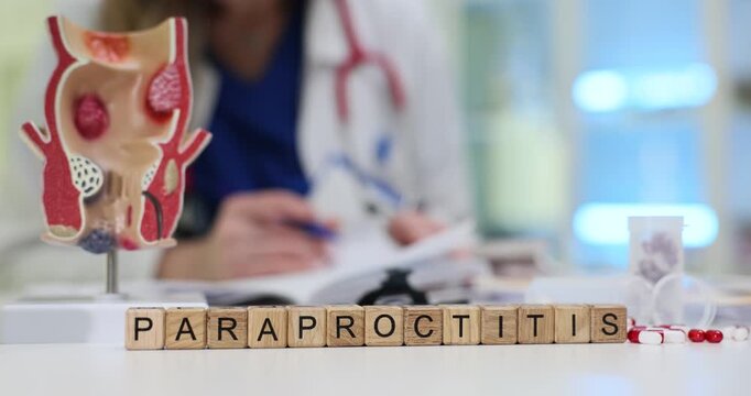Text Paraproctitis on wooden blocks with rectum anatomical model in clinic. Female doctor fills patient medical history after examination in hospital