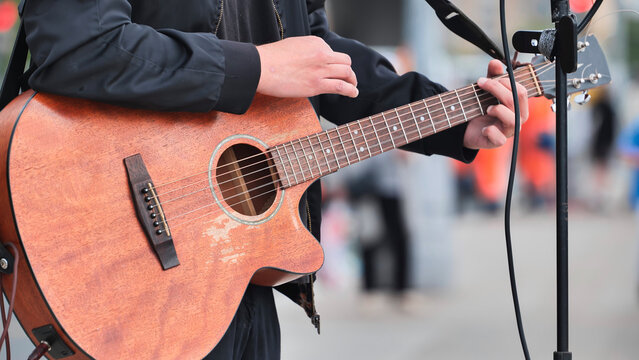Musician playing acoustic guitar during an outdoor street performance