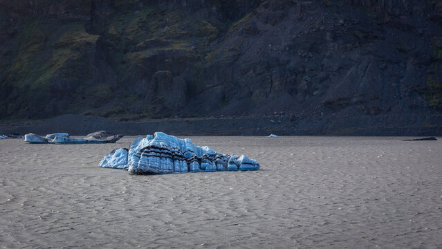 Solheimajokull glacier lagoon blue iceberg with black volcanic ash bands, Iceland