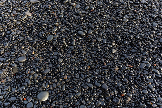 Reynisfjara Black Sand Beach top down texture of wet basalt pebbles and shingle stones, Iceland
