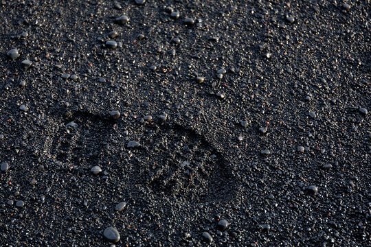 Reynisfjara Black Sand Beach boot footprint on wet volcanic sand and pebbles, Iceland