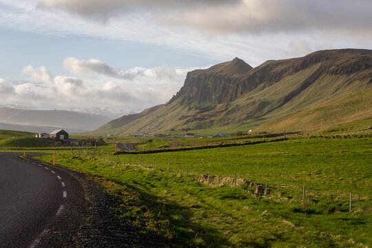 Asphalt curve of the Ring Road passing green grasslands and Eyjafjoll mountains, Iceland