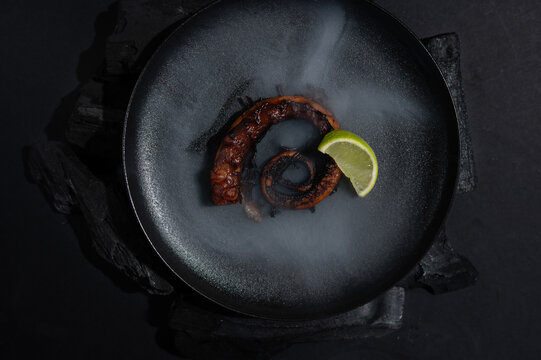 Grilled octopus with lime served on a dark plate
