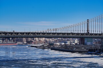 Naklejka premium The Manhattan Bridge and ice floes on the East River in New York City.