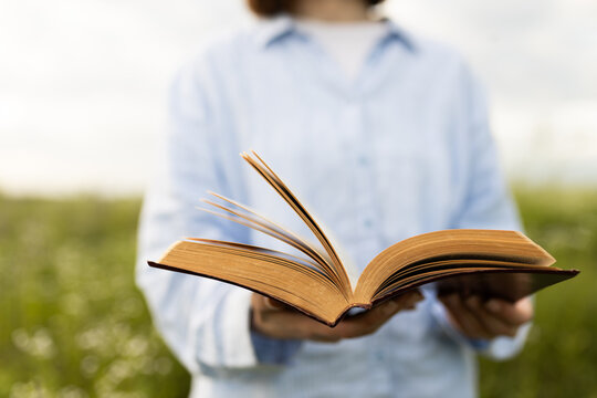 Woman holding open book outdoors in natural setting