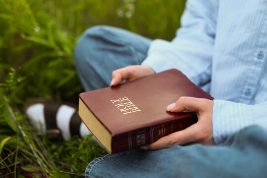 Woman holding a holy Bible in peaceful outdoor setting