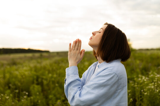 Woman praying in serene countryside setting