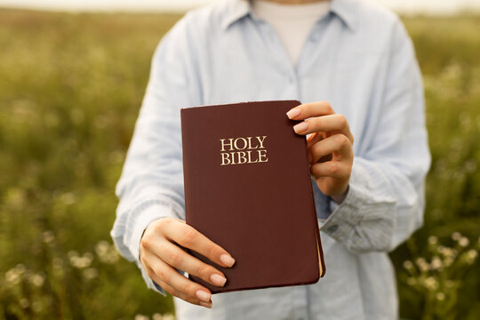 Woman holding a Bible in a serene field