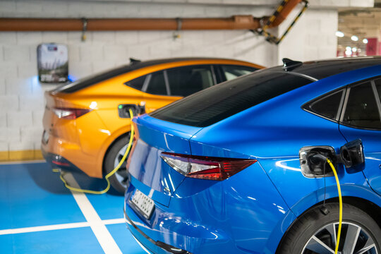 Electric vehicles blue and orange charging in a modern parking garage 