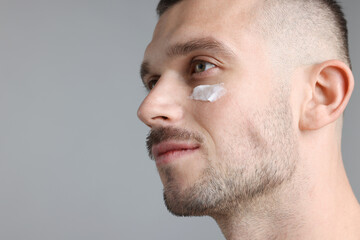 Obraz premium Handsome man with cream on his face against light grey background. Space for text