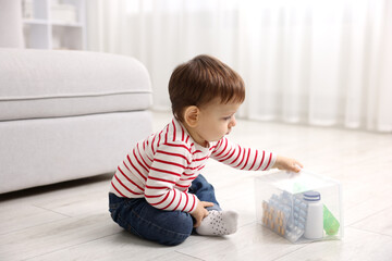 Naklejka premium Child safety at home. Little boy with box of pills indoors