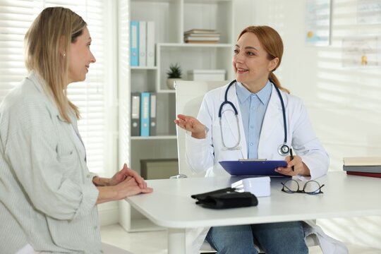 Smiling woman having appointment with cardiologist at table in clinic