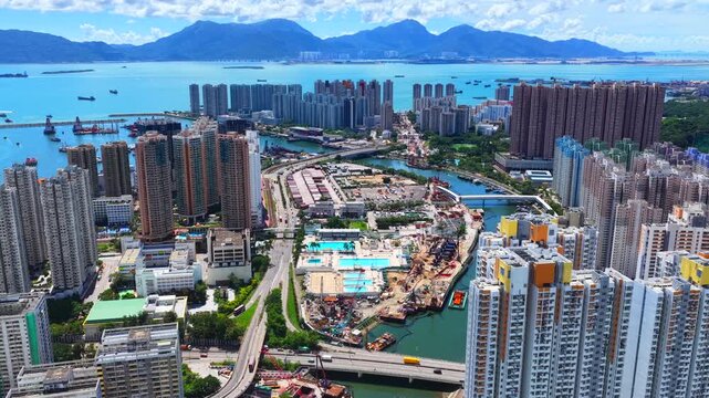 Aerial skyview of Tuen Mun subway extension project in Hong Kong, featuring elevated railway construction along Tuen Mun River and road, new station development and temporary work platforms