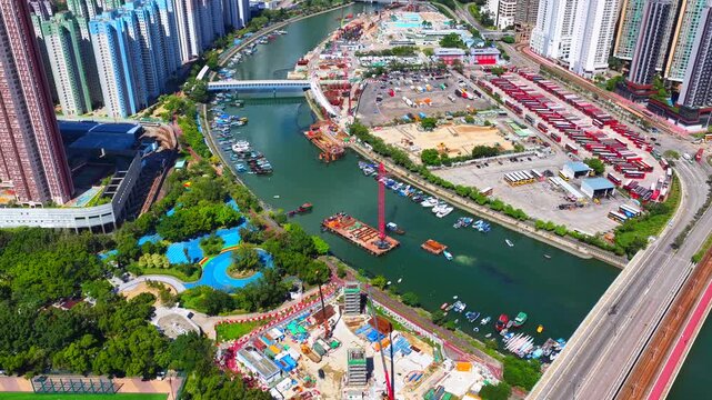 Aerial skyview of Tuen Mun subway extension project in Hong Kong, featuring elevated railway construction along Tuen Mun River and road, new station development and temporary work platforms