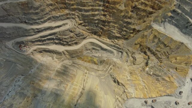 Aerial top view of open pit copper ore mine and heavy mining equipment. Excavator and mining trucks in quarry, 4k