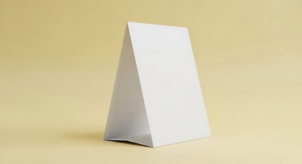 A simple white paper tent card standing upright on a flat surface with a light beige background