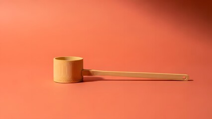 A wooden mallet with a long handle on a salmon-colored background